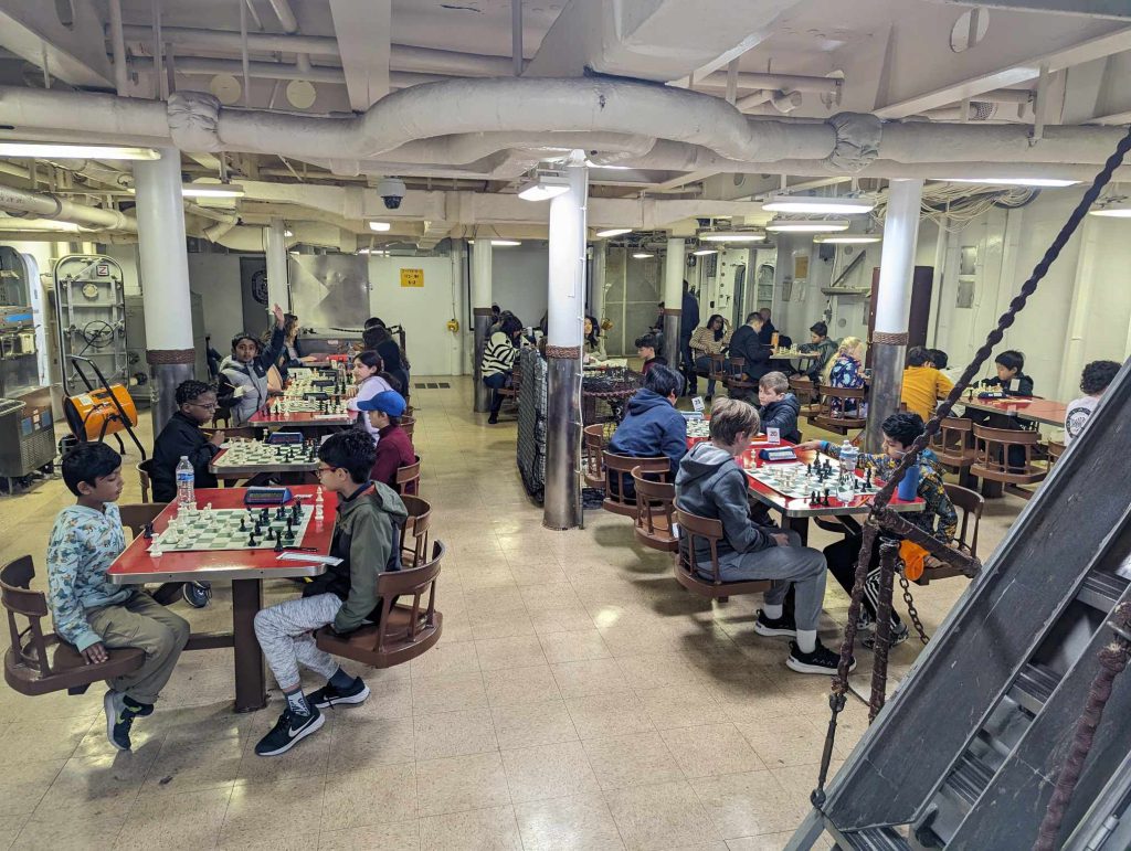 Scholastic chess players participating in a tournament in the mess hall of  the Battleship Wisconsin